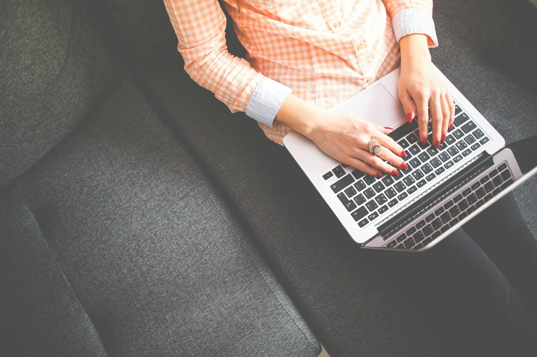 person sitting on gray sofa while using macbook
